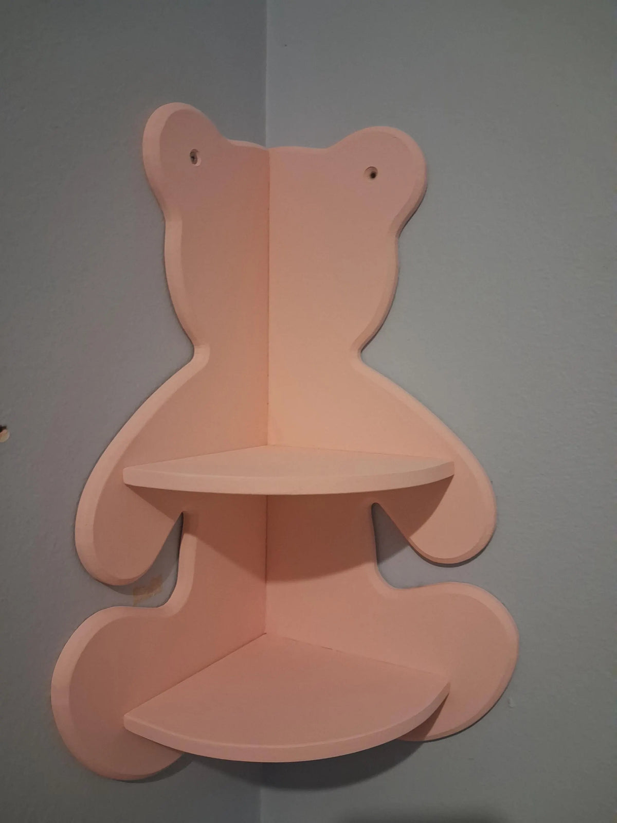 Front view of a pink teddy bear-shaped corner shelf mounted in a wall corner.