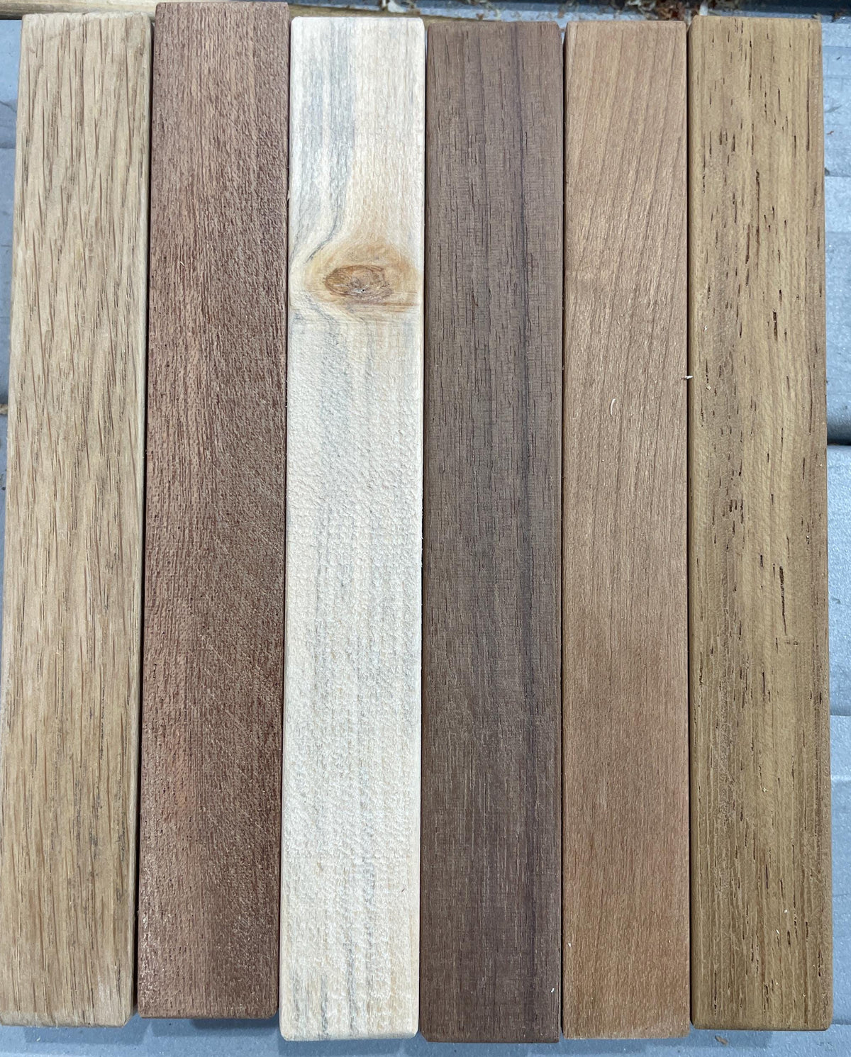 Six vertical wooden planks in various natural wood tones and grain patterns, arranged side-by-side