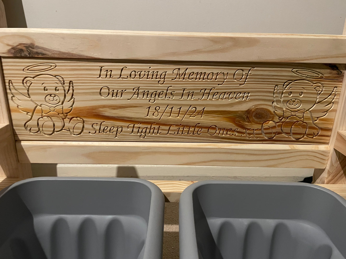 Flower bench untreated with engraved teddy bear illustrations and the text 'In Loving Memory Of Our Angels In Heaven 18/11/24 Sleep Tight Little Ones', shown with two grey pots.